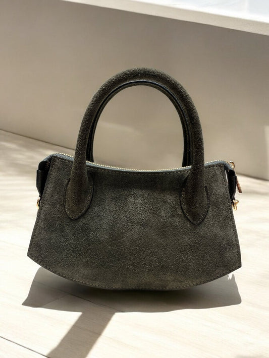 Borsa in pelle scamosciata grigia con maniglie e tracolla regolabile, dettagli metallici dorati, elegante e versatile.
